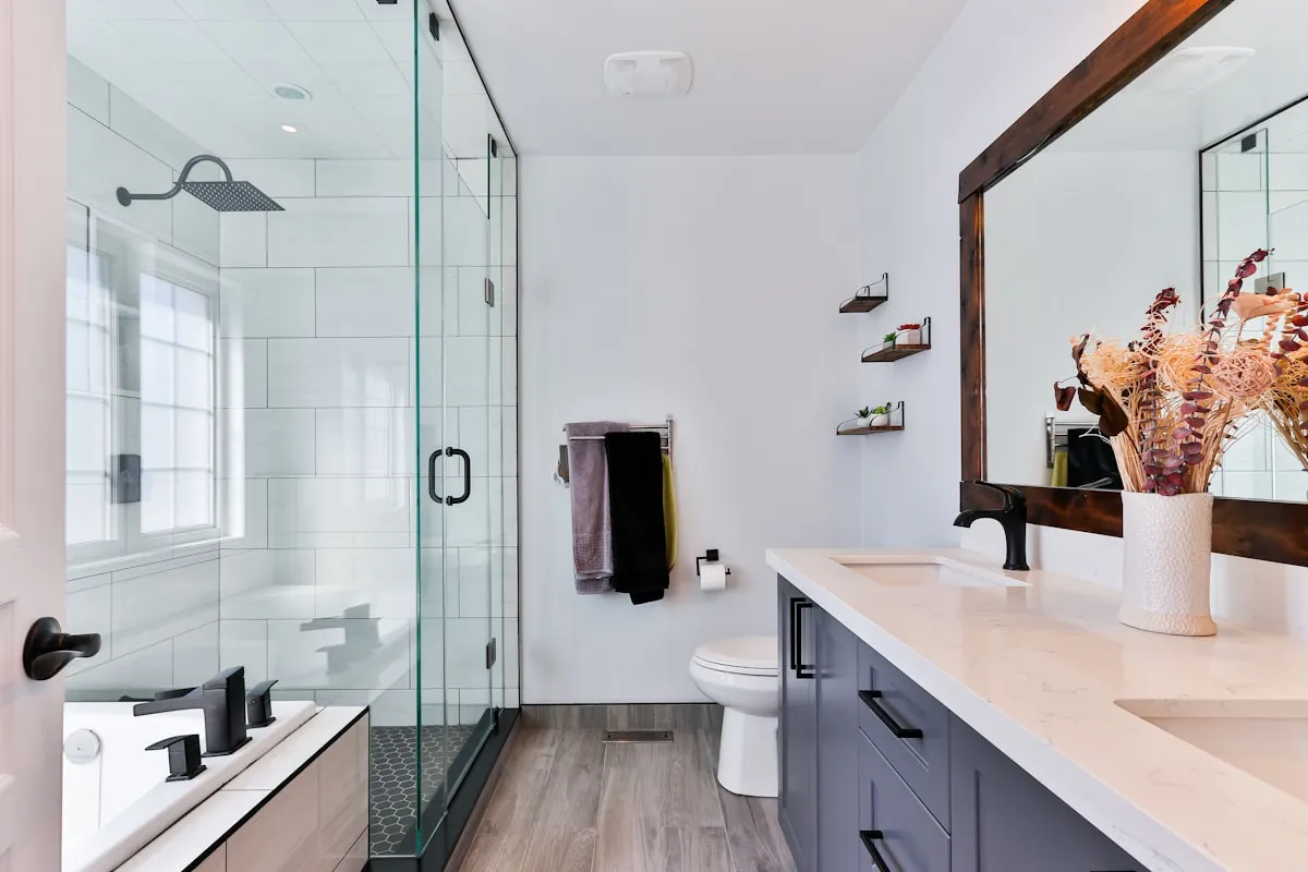 Modern bathroom with matte black faucets, double vanity sinks, rainfall showerhead, and tub fixtures professionally installed