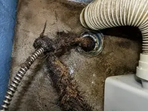 Professional drain snaking cable clearing a localized pipe blockage