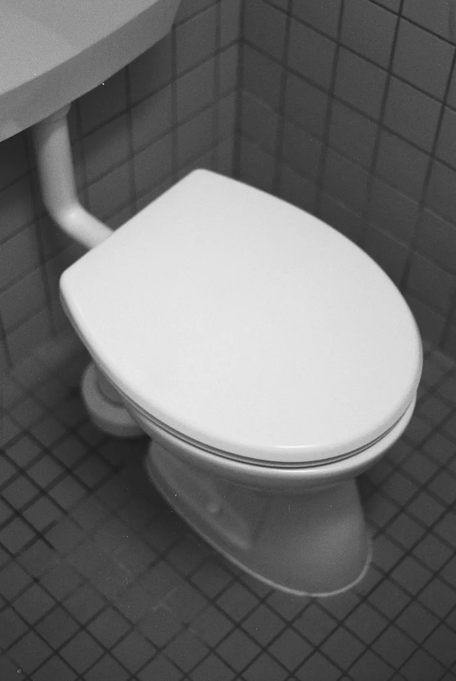 White porcelain toilet in a tiled bathroom that may need professional clog clearing and overflow repair